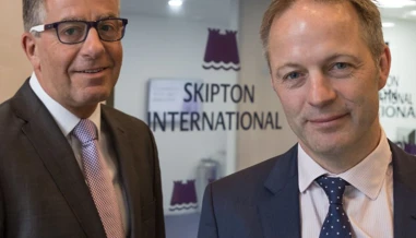 Two men smiling Infront of Skipton logo