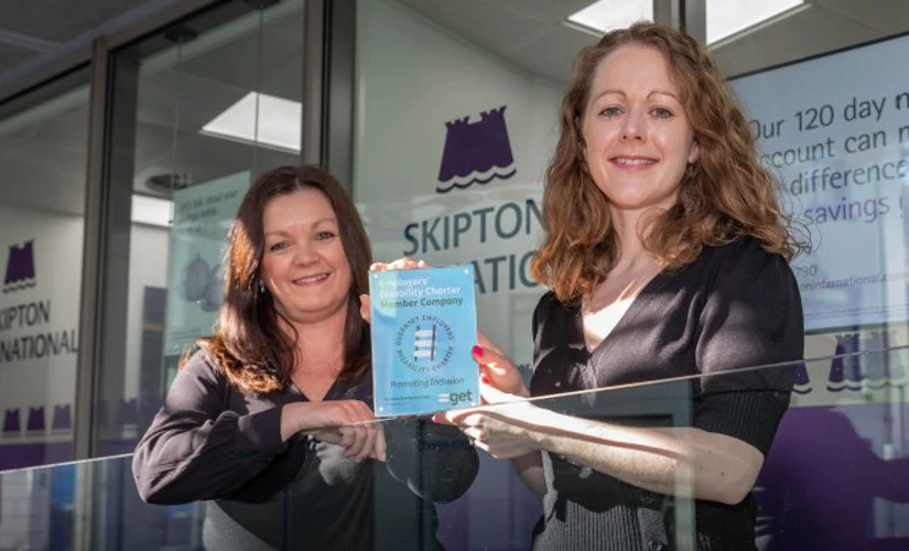 people smiling in front of Skipton office with award