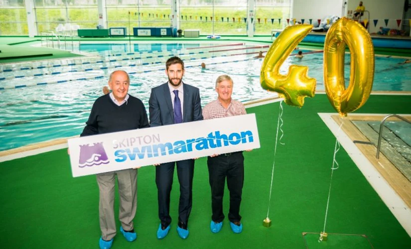 People holding Swimarathon sign next to 40 balloons