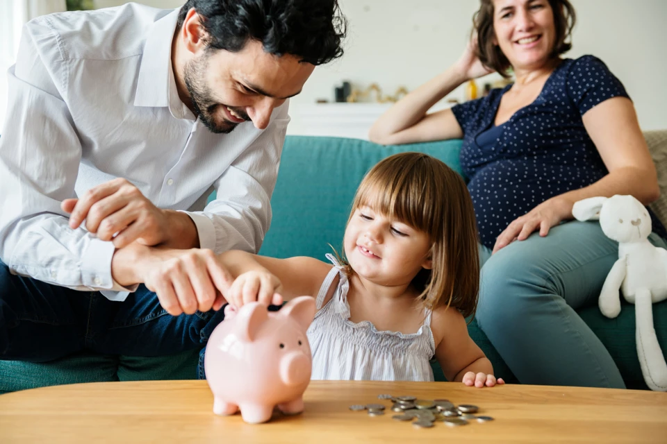 Family and child putting coins in a piggy bank