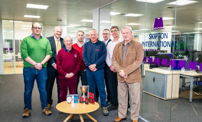 people smiling in front of Skipton logo