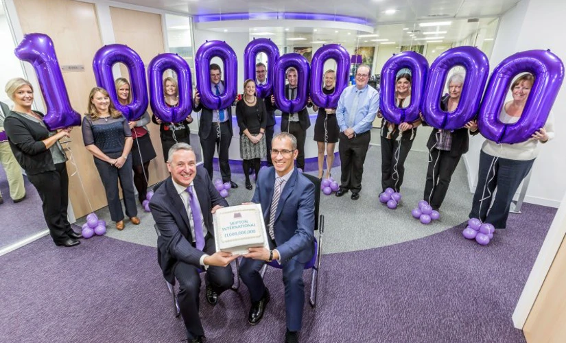 People holding up the number one billion on balloons