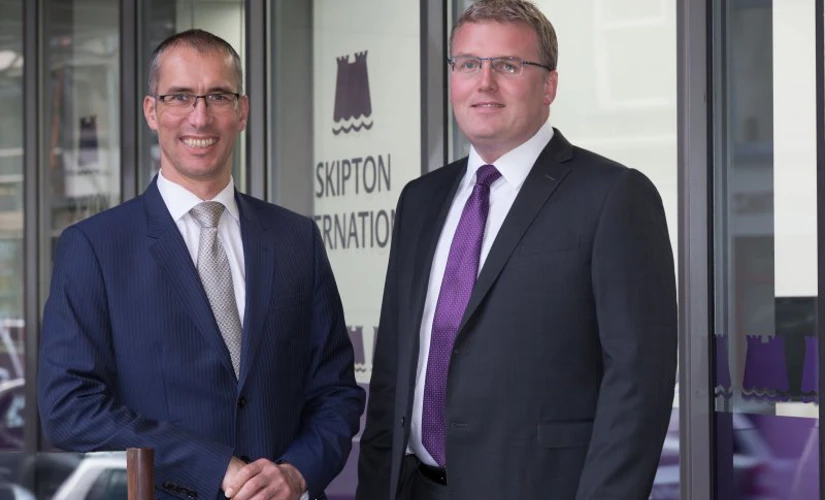 Two men in front of Skipton International Limited building