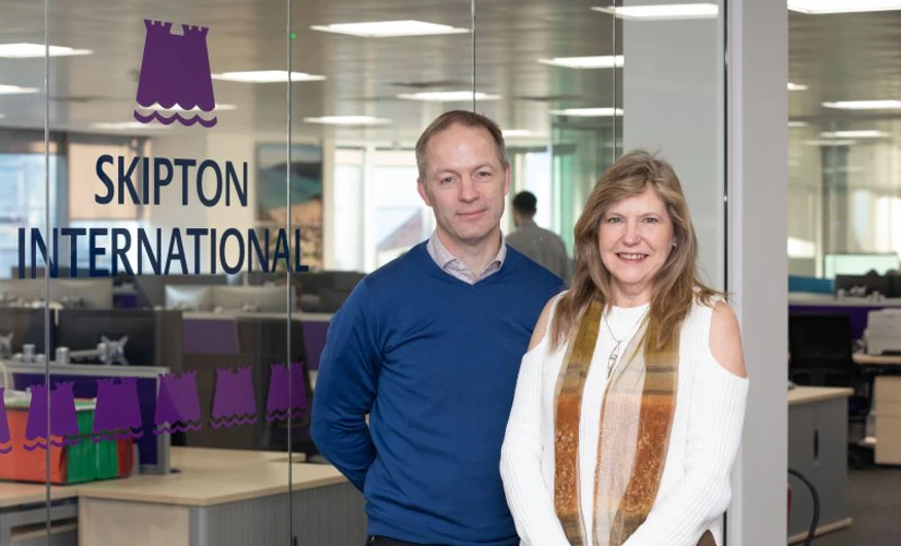 people smiling in front of Skipton logo