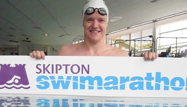 Person in water holding Swimarathon sign