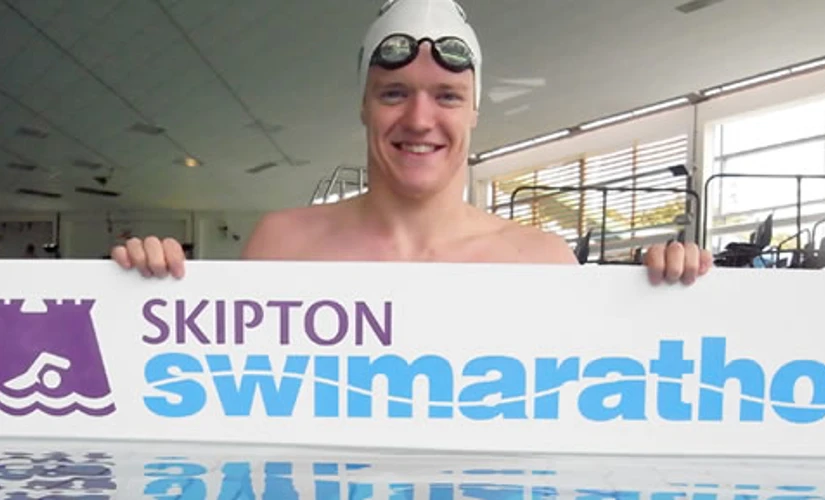 Person in water holding Swimarathon sign