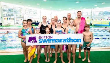 Group of swimmers posing with Skipton Swimarathon logo