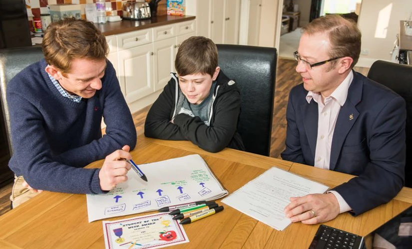 two men site alongside child looking at papers