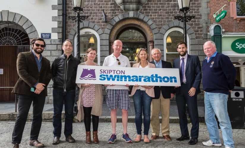 people smiling in front of Skipton Swimarathon logo