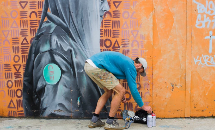 Man bending over to pick up spray paint