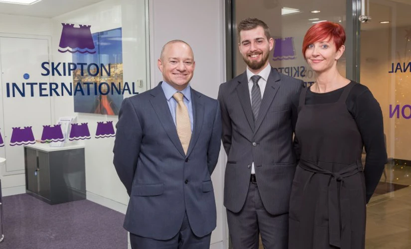 people smiling in front of Skipton logo