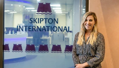 person standing in front of skipton international logo