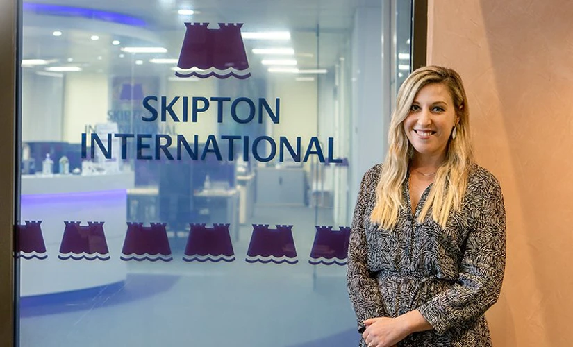 person standing in front of skipton international logo
