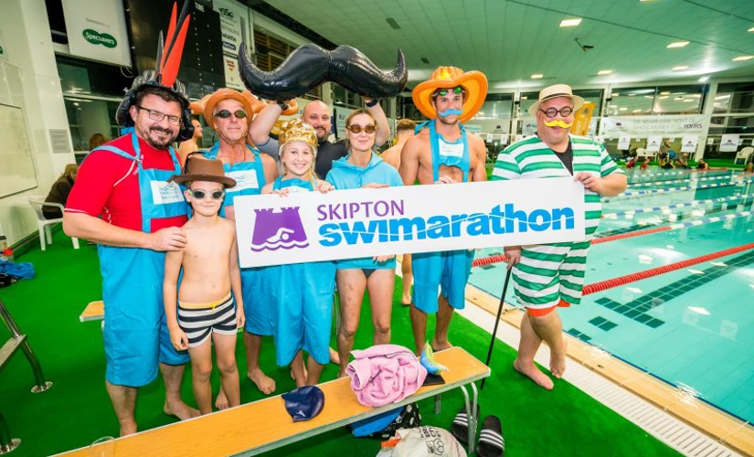 People dressed up holding Swimarathon sign