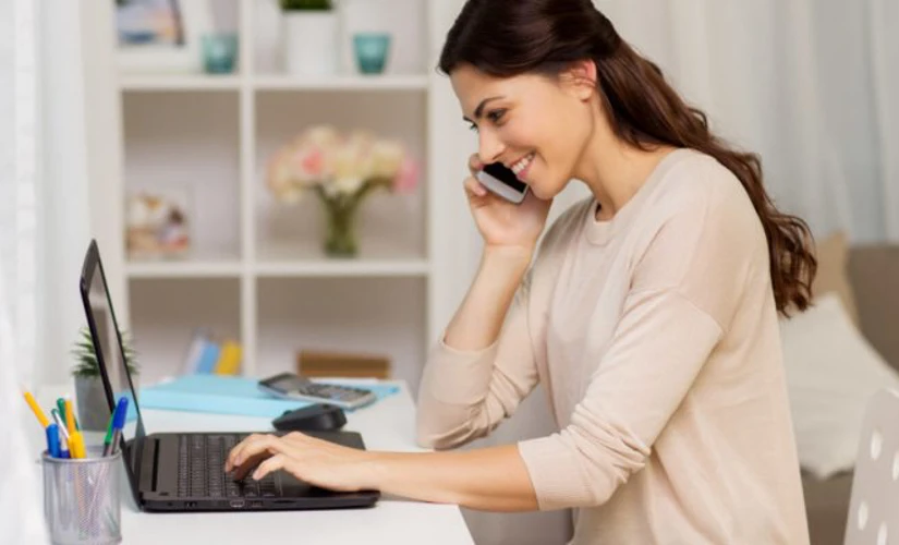 women smiling on the phone looking at computer