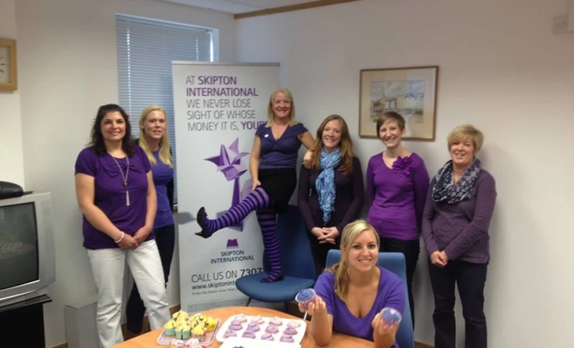 People in front of Skipton International Limited banner