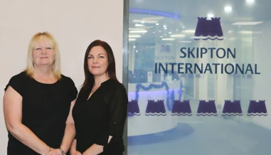 two women smiling Infront of Skipton International logo