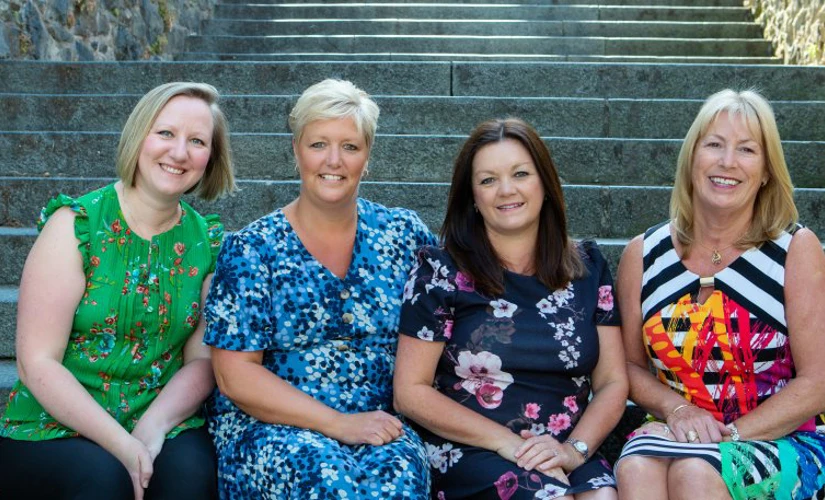 four women smiling on stone stairs