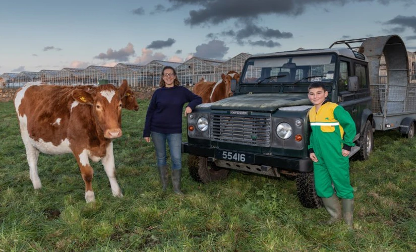 women and child pose in front of car alongside a cow