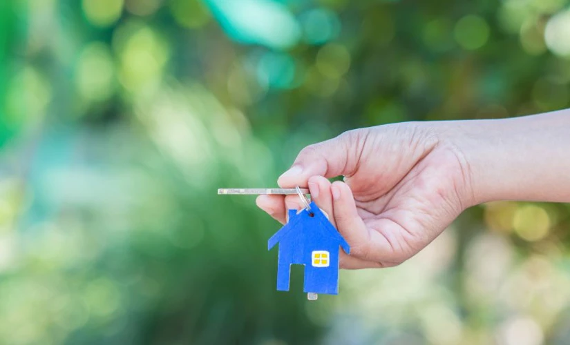 people holding keys with house keychain