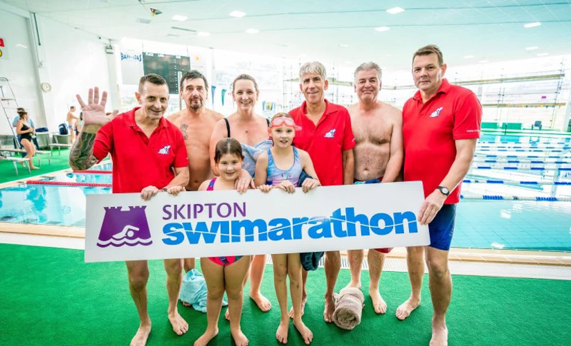 people smiling in front of Skipton Swimarathon logo