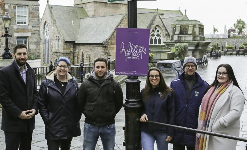 Six people photographed by sign