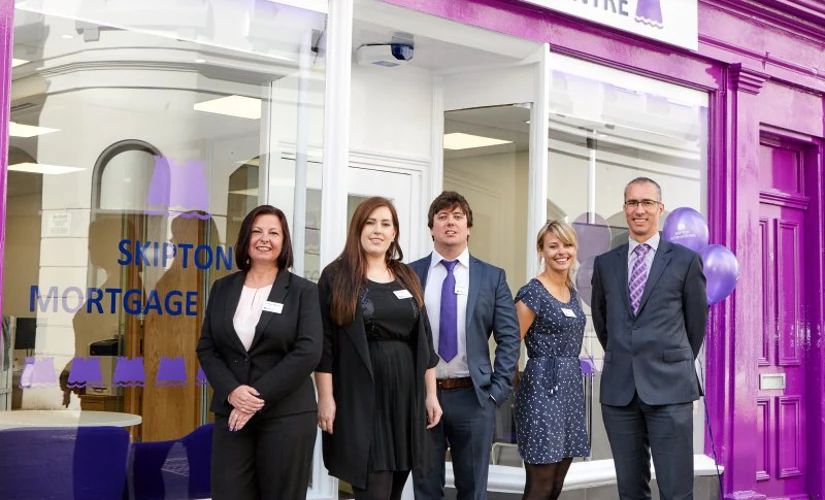 people smiling in front of Skipton logo