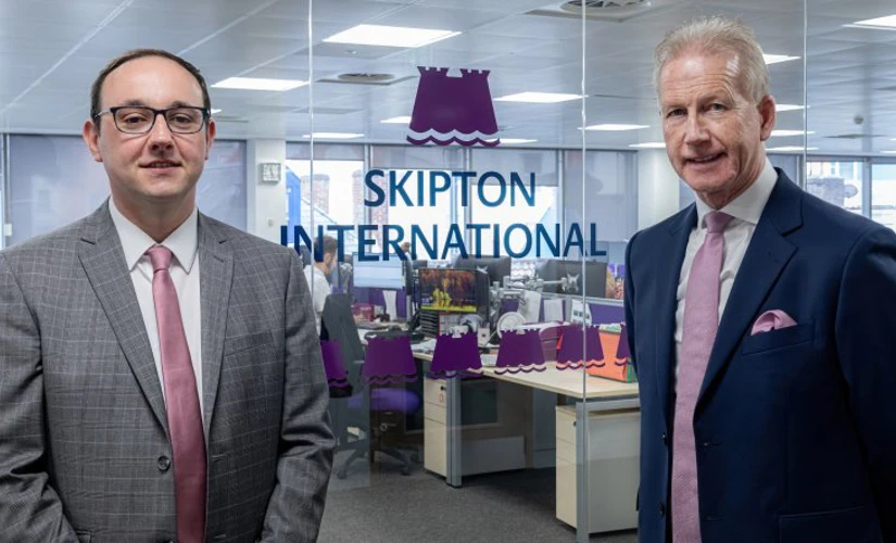 people smiling in front of Skipton logo